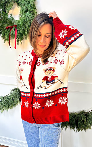 Woman wearing ivory sweater with teddy bear skiers and snowflake accents